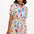 A model wearing a short-sleeved shirt dress with a tie-front belt and a multicolored jungle tile print.
