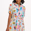 A model wearing a short-sleeved shirt dress with a tie-front belt and a multicolored jungle tile print.