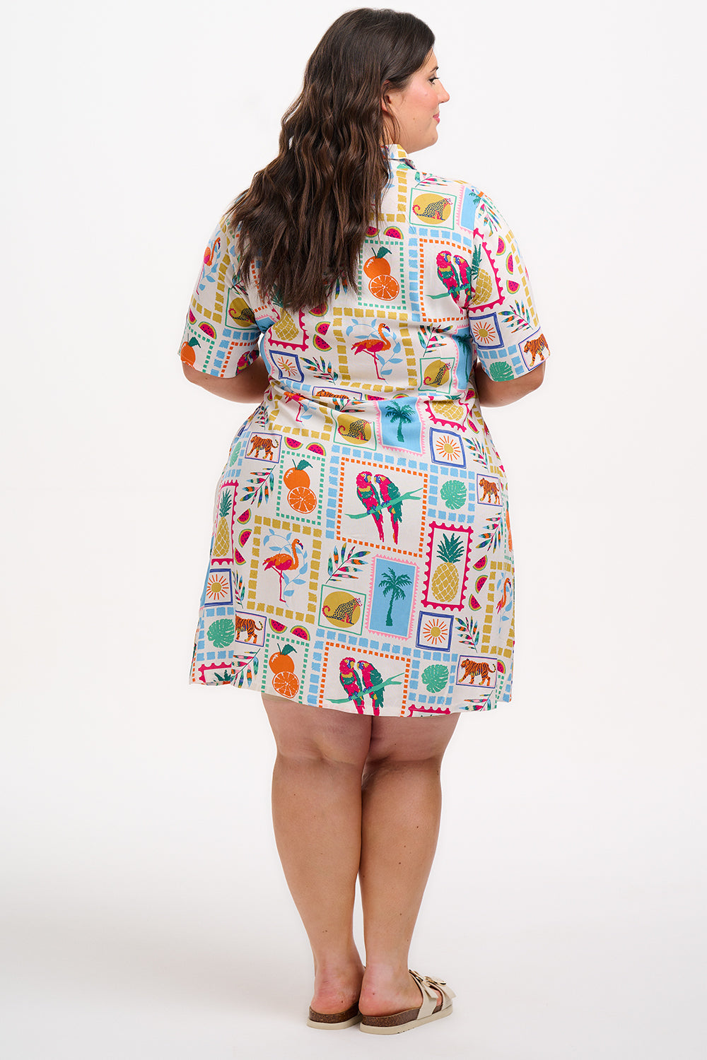 A model wearing a short-sleeved shirt dress with a tie-front belt and a multicolored jungle tile print.