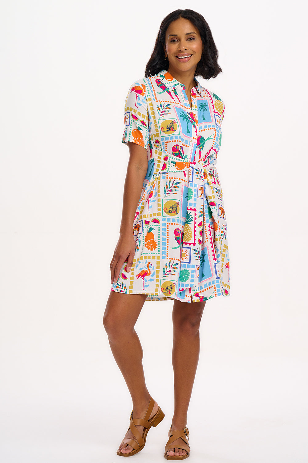 A model wearing a short-sleeved shirt dress with a tie-front belt and a multicolored jungle tile print.