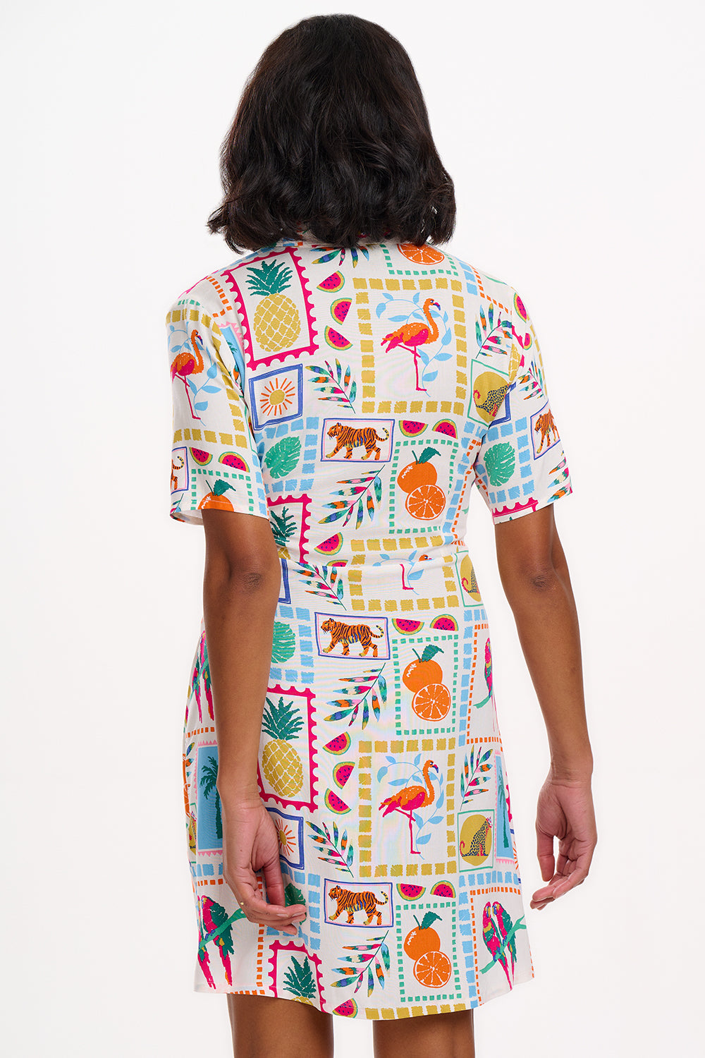 A model wearing a short-sleeved shirt dress with a tie-front belt and a multicolored jungle tile print.
