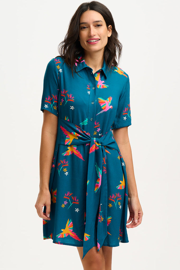 A model wearing a teal shirt dress with a Rainbow Parrots print, featuring short sleeves and a tie-front belt.