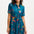A model wearing a teal shirt dress with a Rainbow Parrots print, featuring short sleeves and a tie-front belt.