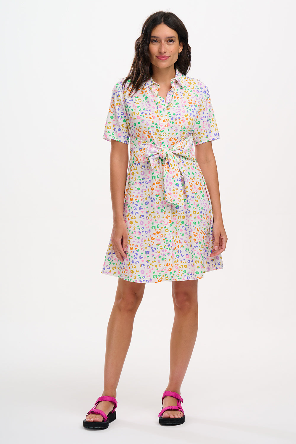 A model wearing an off-white shirt dress with a mottled leopard print, featuring a button-up front, short sleeves, and a tie-front belt.
