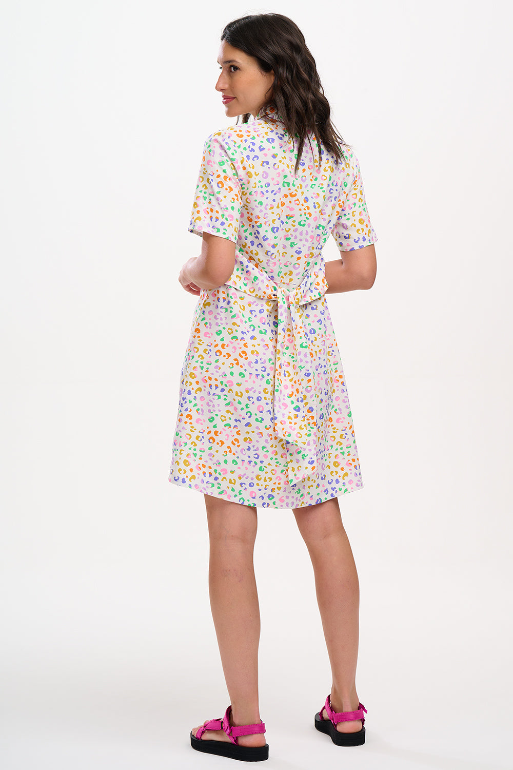 A model wearing an off-white shirt dress with a mottled leopard print, featuring a button-up front, short sleeves, and a tie-front belt.