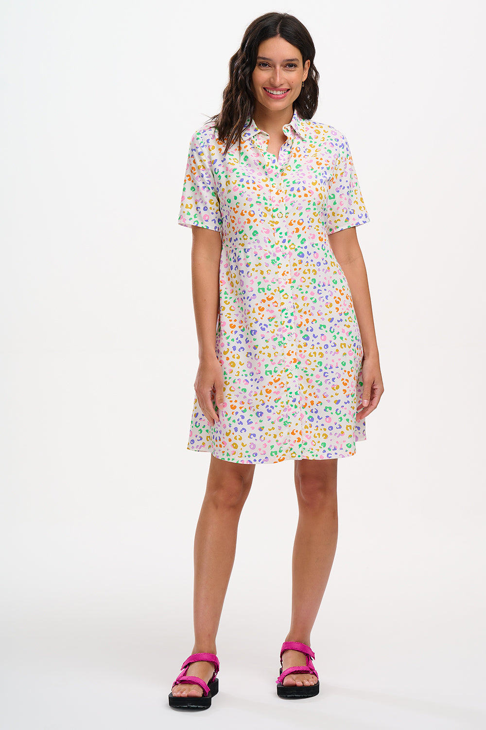 A model wearing an off-white shirt dress with a mottled leopard print, featuring a button-up front, short sleeves, and a tie-front belt.