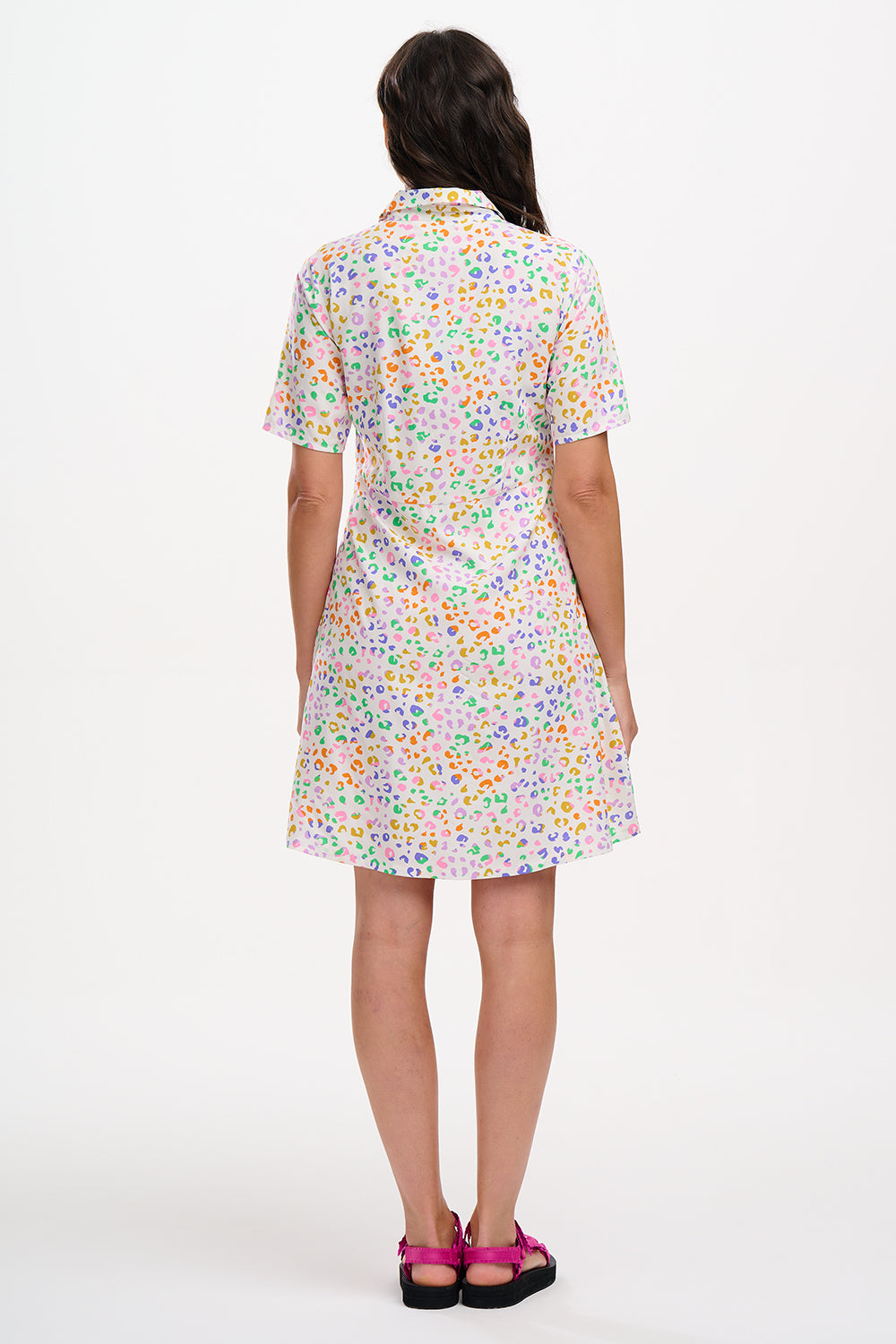 A model wearing an off-white shirt dress with a mottled leopard print, featuring a button-up front, short sleeves, and a tie-front belt.