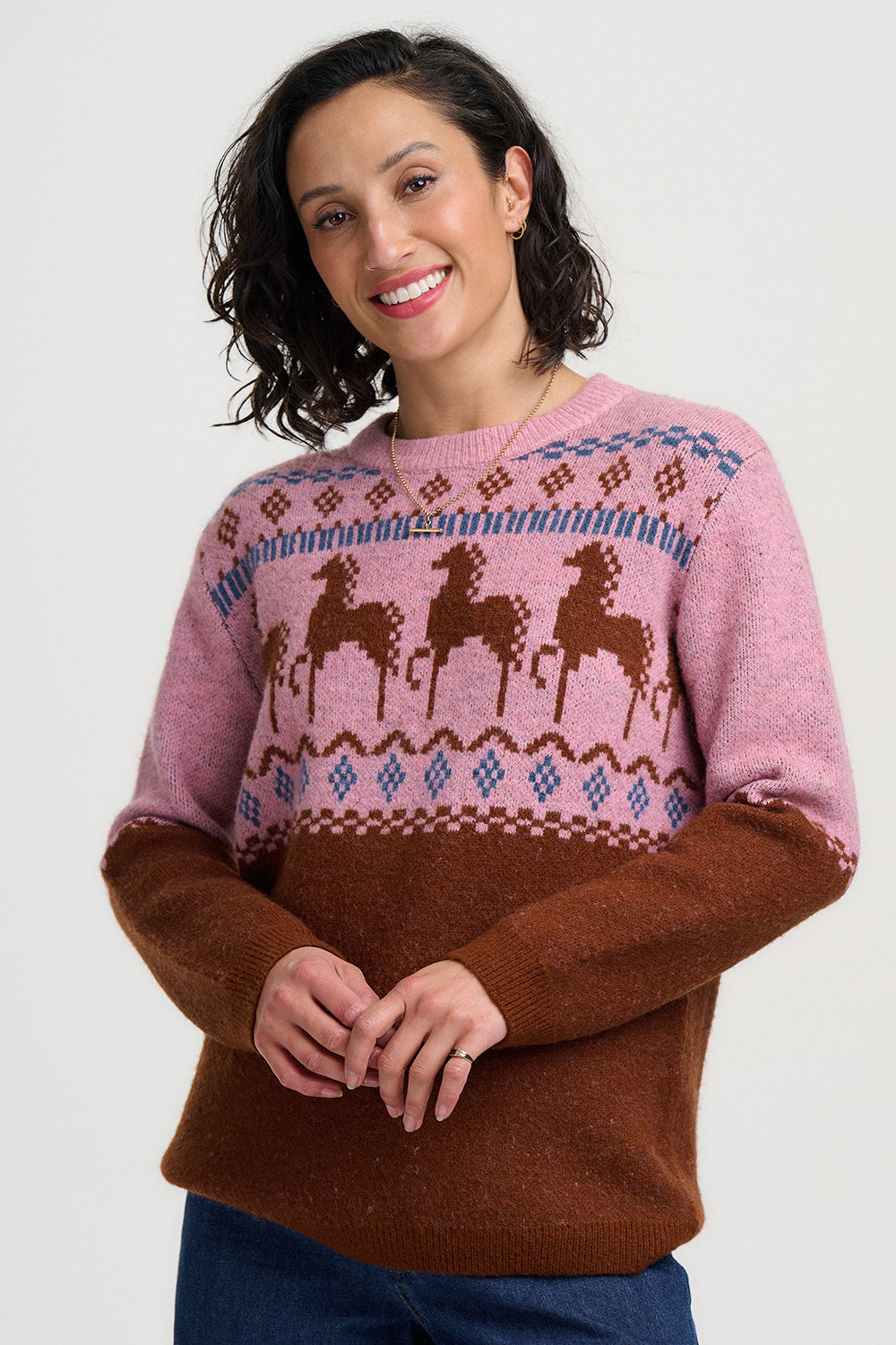 Woman wearing a pink and brown sweater with deer pattern on a white background