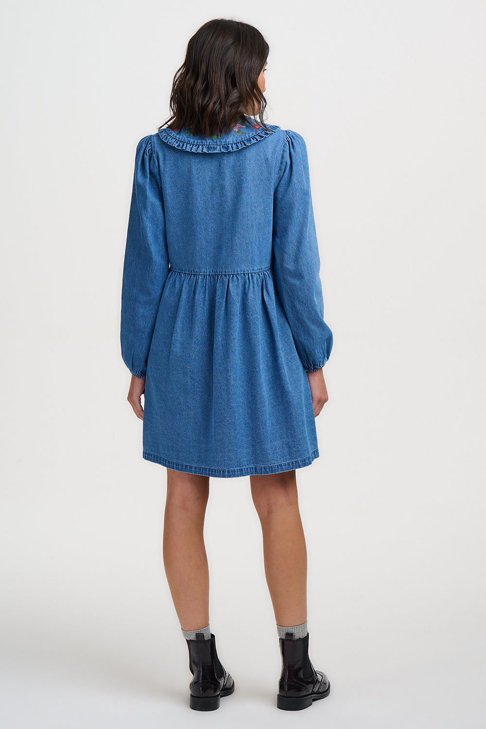 Blue denim dress worn by a person on a white background