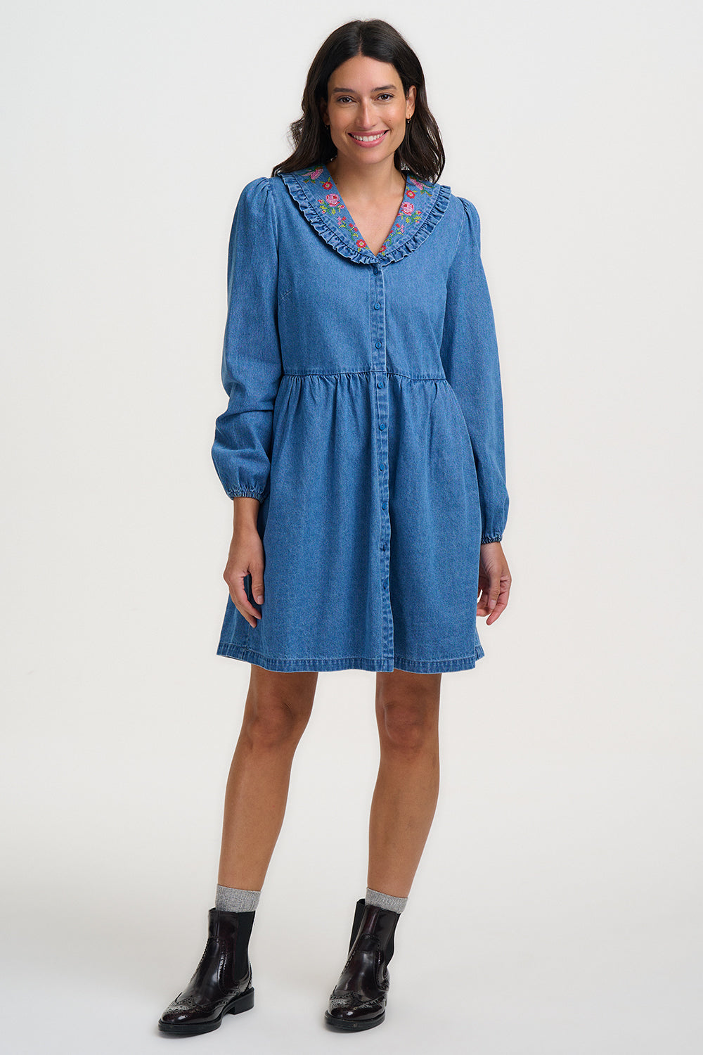 Woman wearing a blue denim dress with a white background