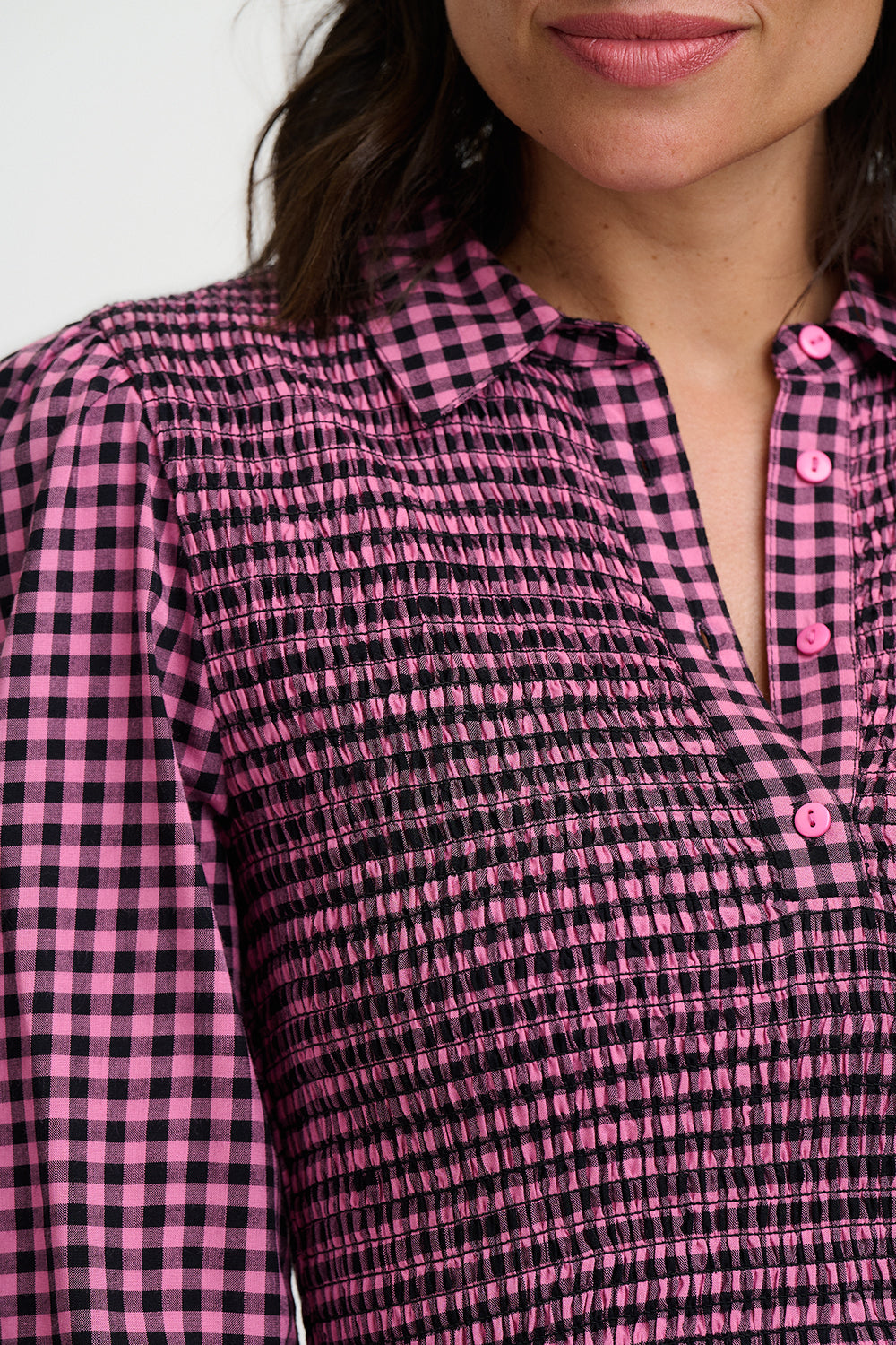 Close-up of a person wearing a pink and black checkered shirt.