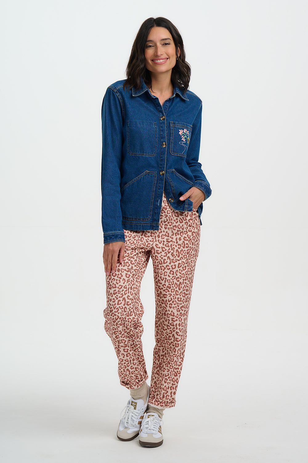 Woman wearing a blue denim jacket and leopard print pants on a white background