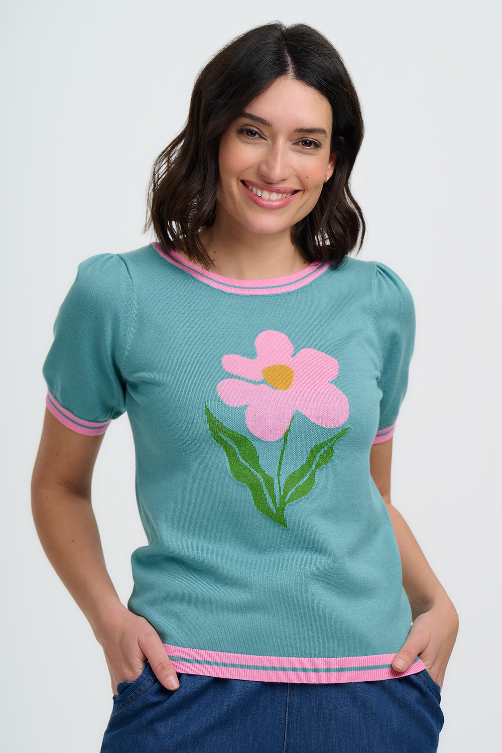 Woman wearing a teal t-shirt with a pink flower design on a white background