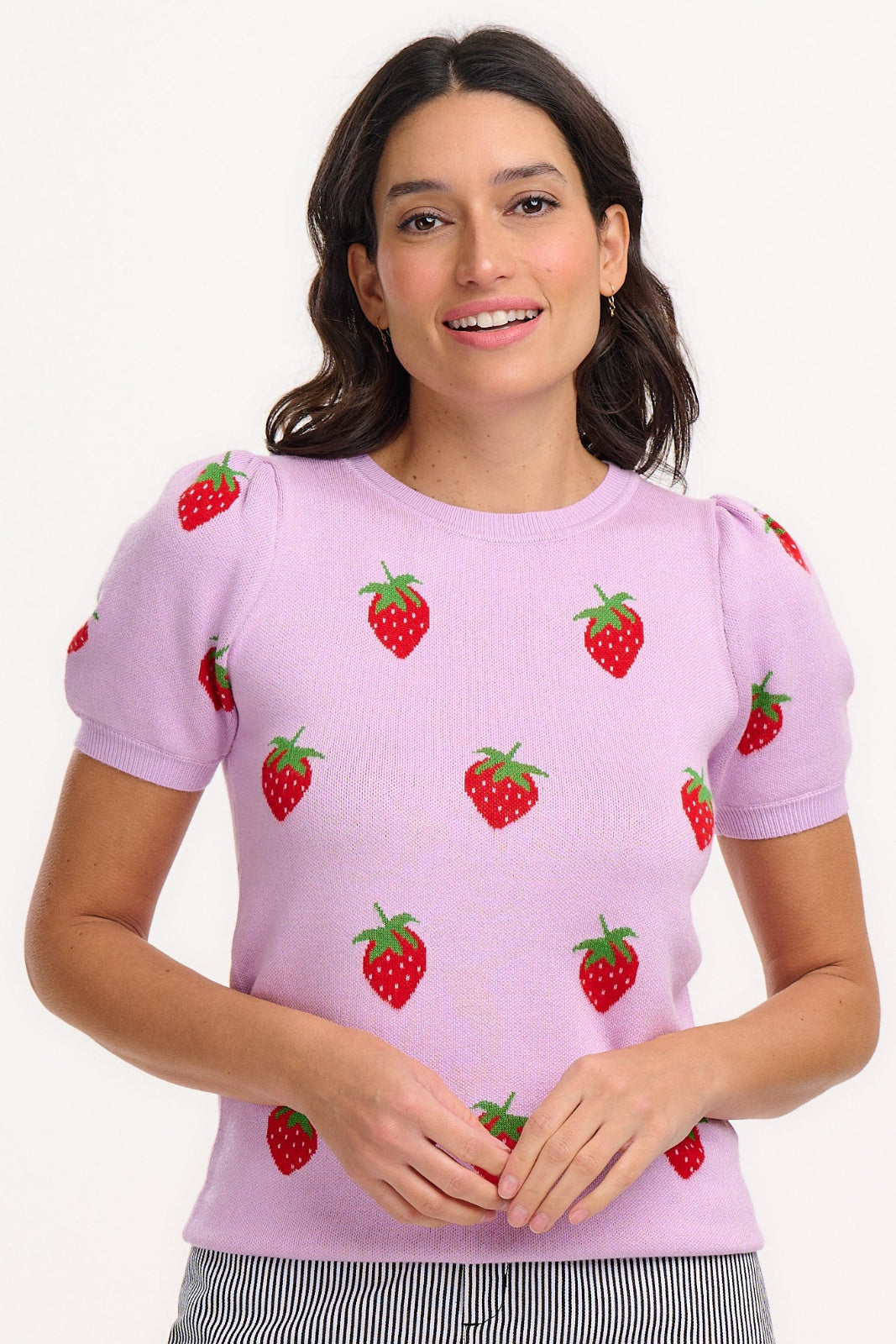 A woman wearing a lilac-colored knit top with a pattern of vibrant strawberries.