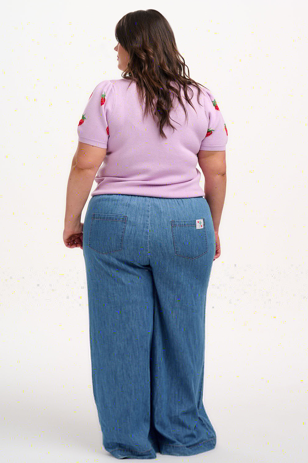 A woman wearing a lilac-colored knit top with a pattern of vibrant strawberries.