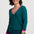 Woman wearing a teal sweater with colorful cuffs and hem on a white background