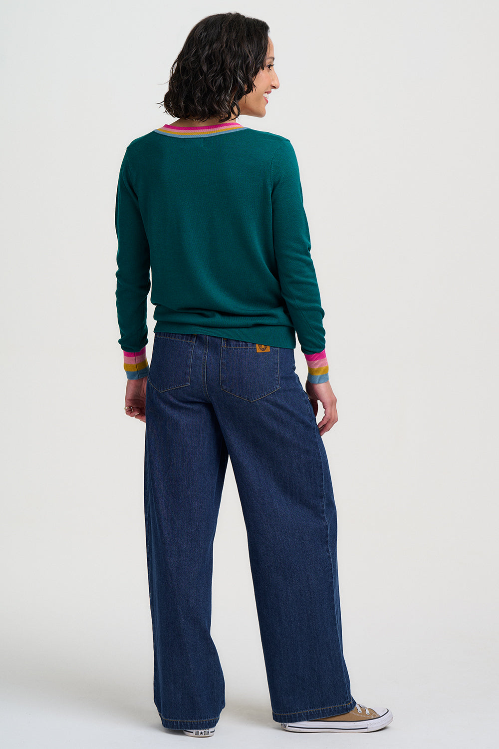 Person wearing a green sweater and blue jeans on a white background