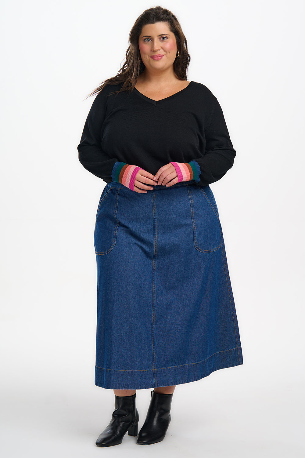 Woman wearing a black top and blue denim skirt on a white background