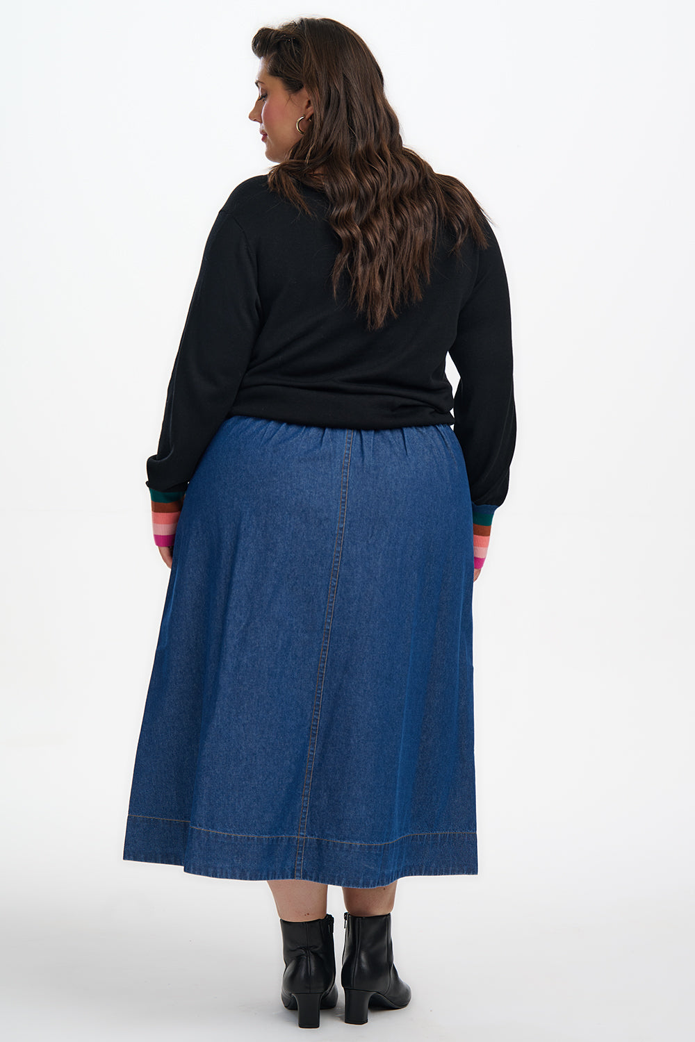 Person wearing a black top and blue skirt on a white background