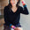 Sugarhill Brighton model wearing a black V-neck jumper with multicoloured stripe cuffs, paired with blue jeans.