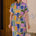 Woman wearing a colorful geometric patterned dress standing against a textured wall.