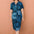 Woman wearing a blue patterned dress against a brown wall