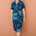 Woman wearing a blue patterned dress against a brown wall
