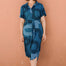 Woman wearing a blue patterned dress against a brown wall
