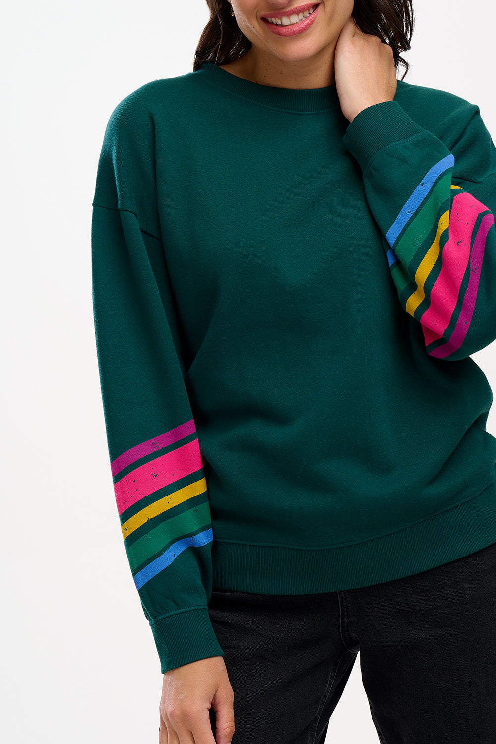 A Sugarhill Brighton model wearing a dark green crew neck sweatshirt with colourful striped sleeves.