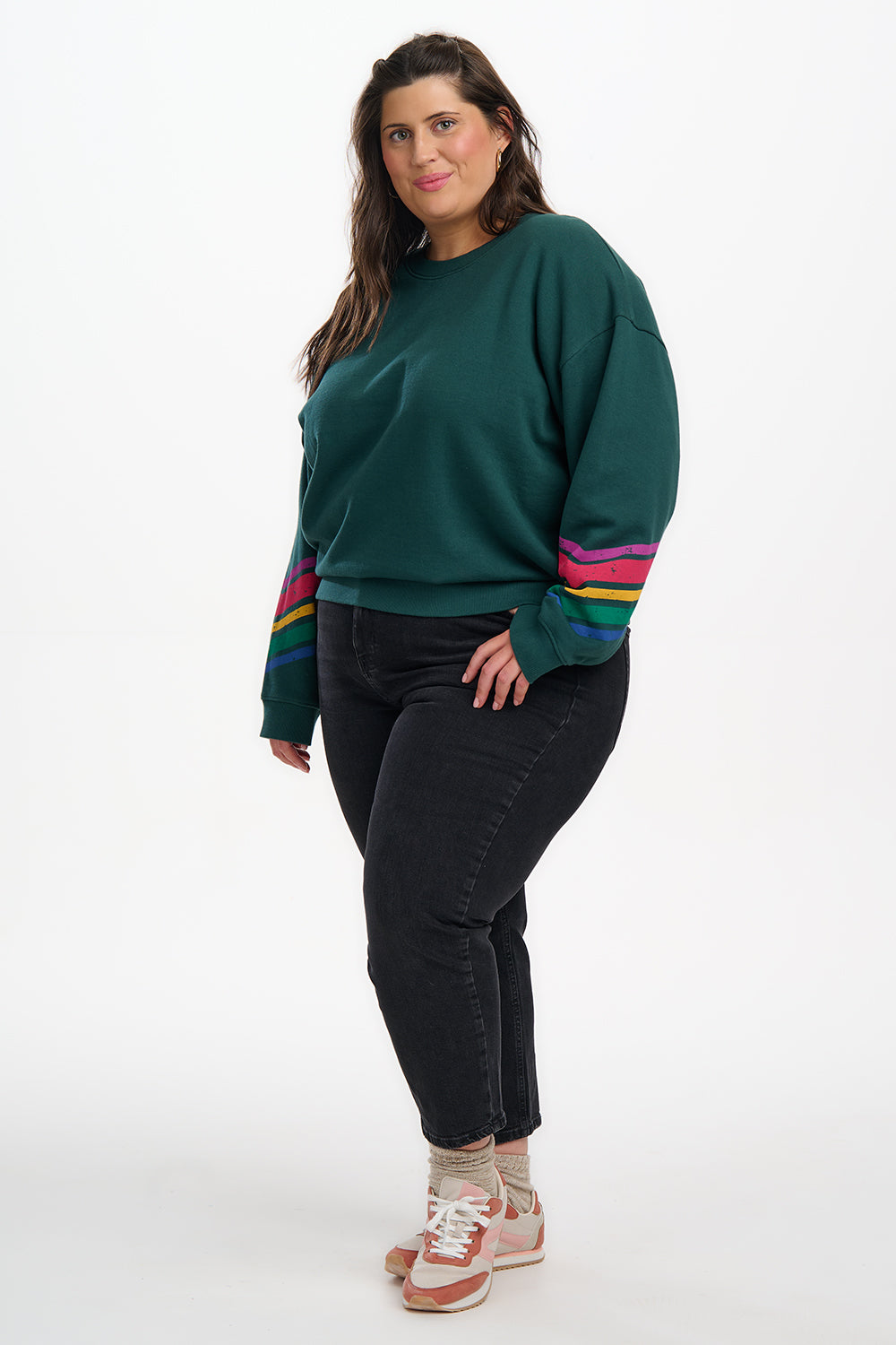 Woman wearing a green sweater with colorful stripes on a white background