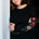 Woman wearing a black sweatshirt with floral designs and teal pants on a white background