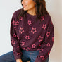 Woman wearing a dark purple sweater with pink star patterns against a plain background