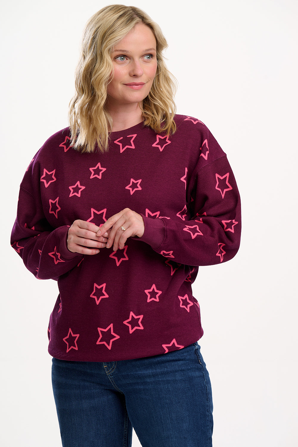 Woman wearing a maroon sweater with pink star patterns on a white background
