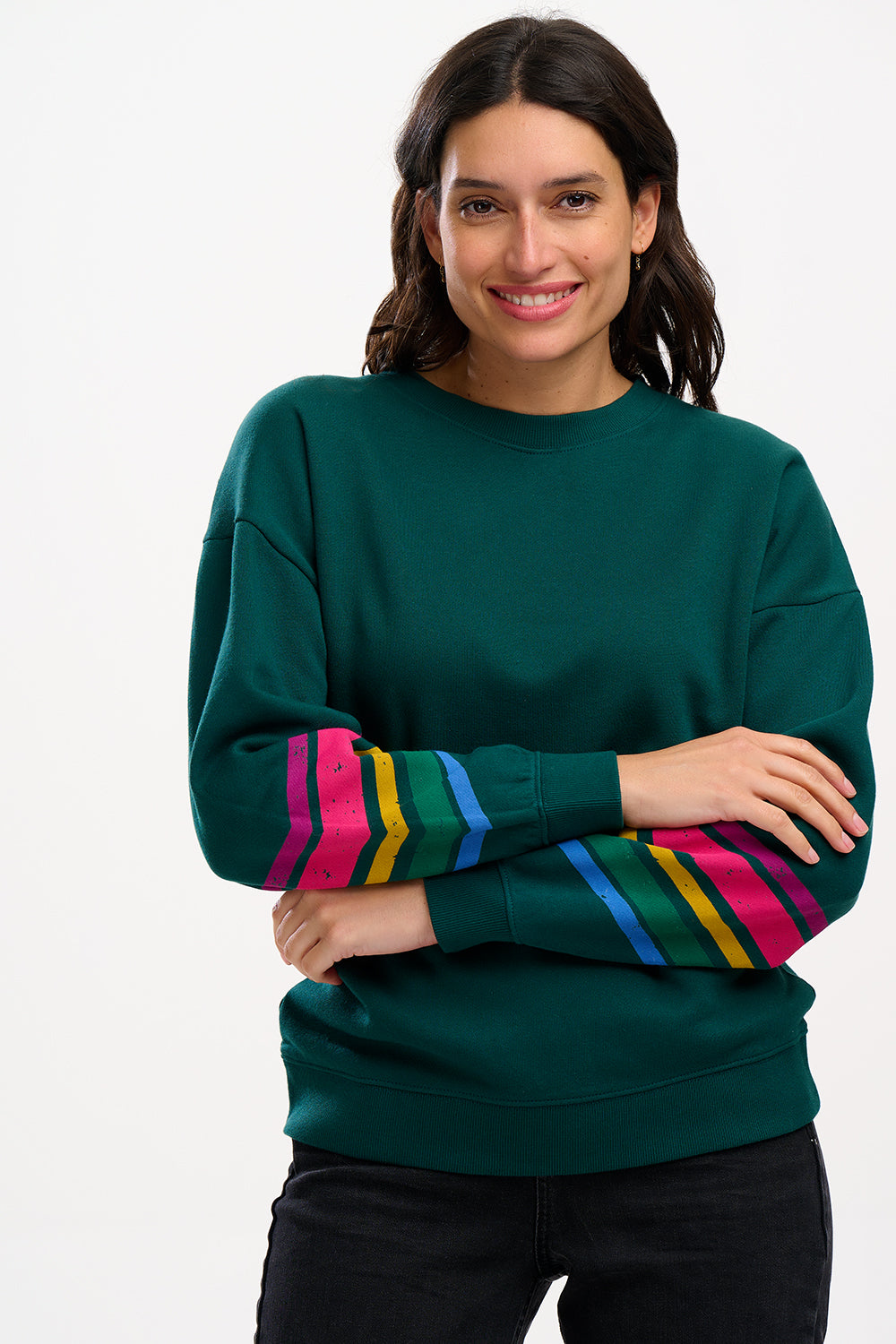 A Sugarhill Brighton model wearing a dark green crew neck sweatshirt with colourful striped sleeves.