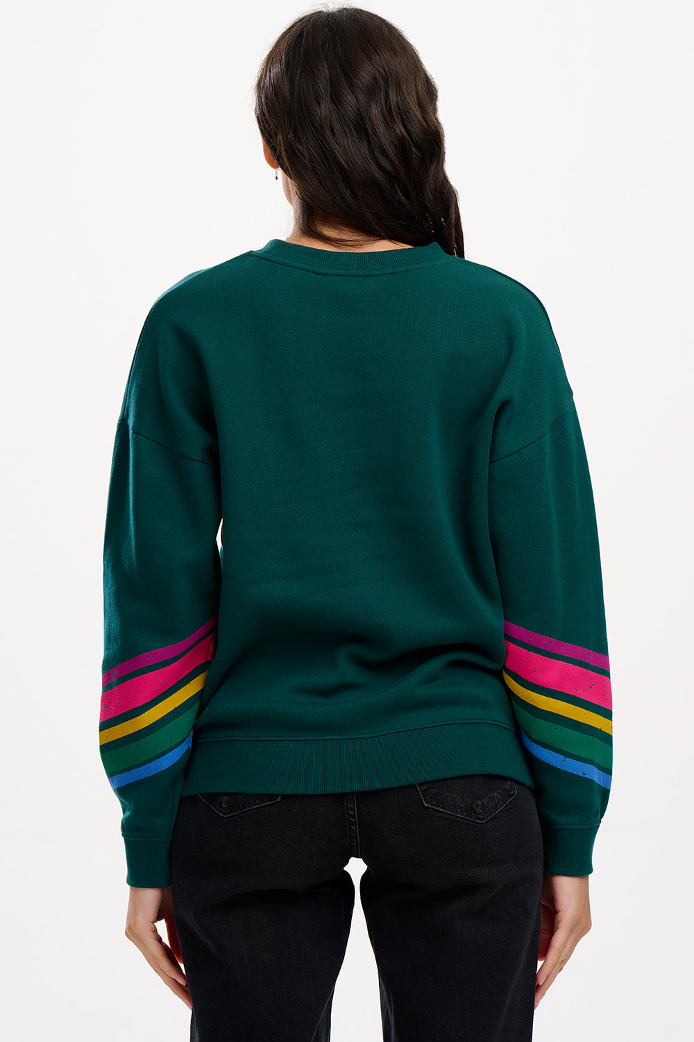 A Sugarhill Brighton model wearing a dark green crew neck sweatshirt with colourful striped sleeves.