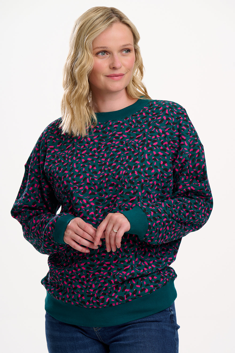 Woman wearing a dark green sweater with pink pattern on a white background