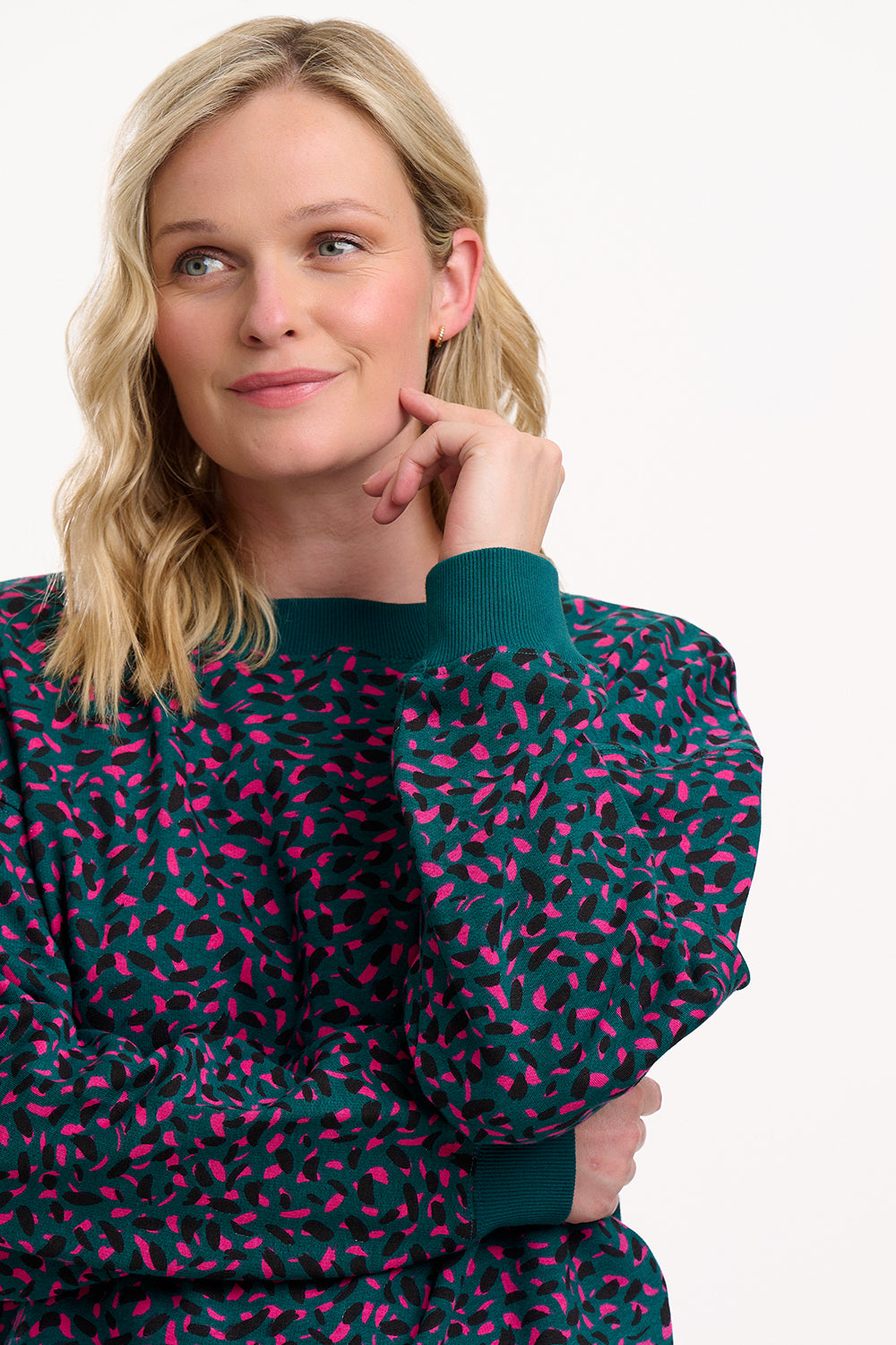 Woman wearing a dark green sweater with pink pattern on a white background