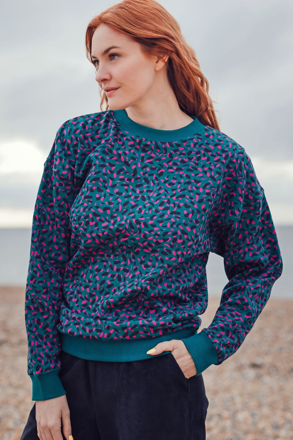 Woman wearing a patterned sweater standing on a beach