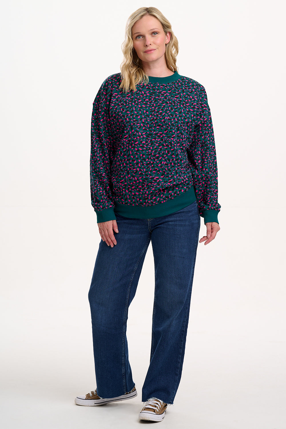 Woman wearing a patterned sweater and blue jeans on a white background