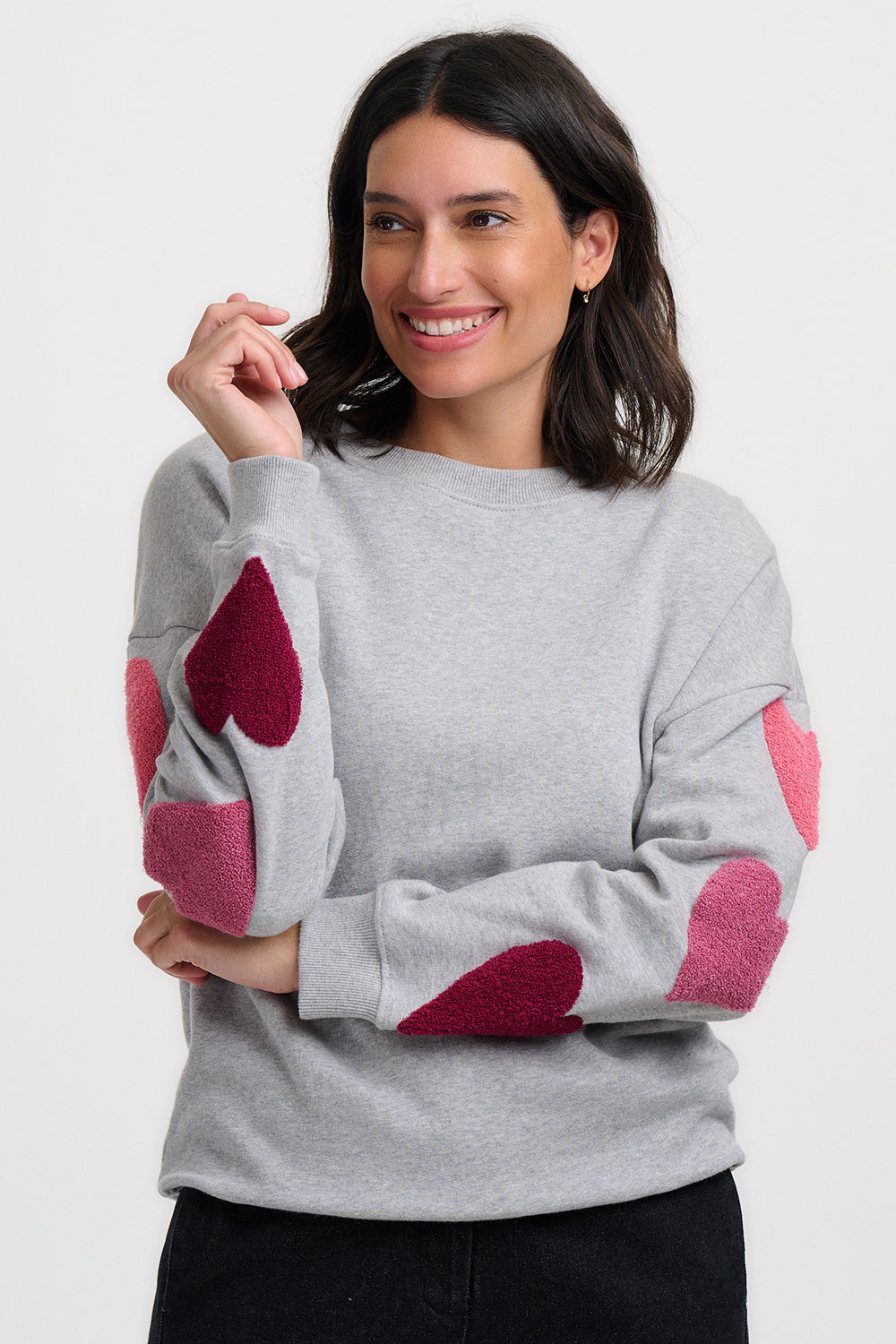 Woman wearing a gray sweater with pink heart patterns on a white background