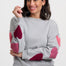 Woman wearing a gray sweater with pink heart patterns on a white background