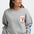 Woman wearing a gray sweatshirt with a lobster patch on a white background
