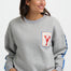 Woman wearing a gray sweatshirt with a lobster patch on a white background