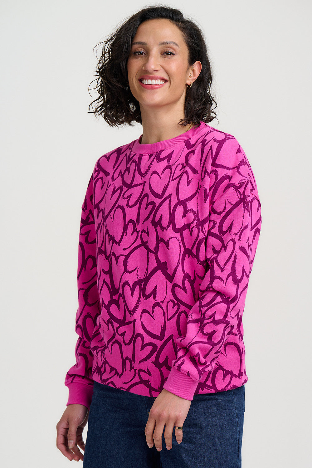 Woman wearing a pink sweatshirt with black heart patterns on a white background