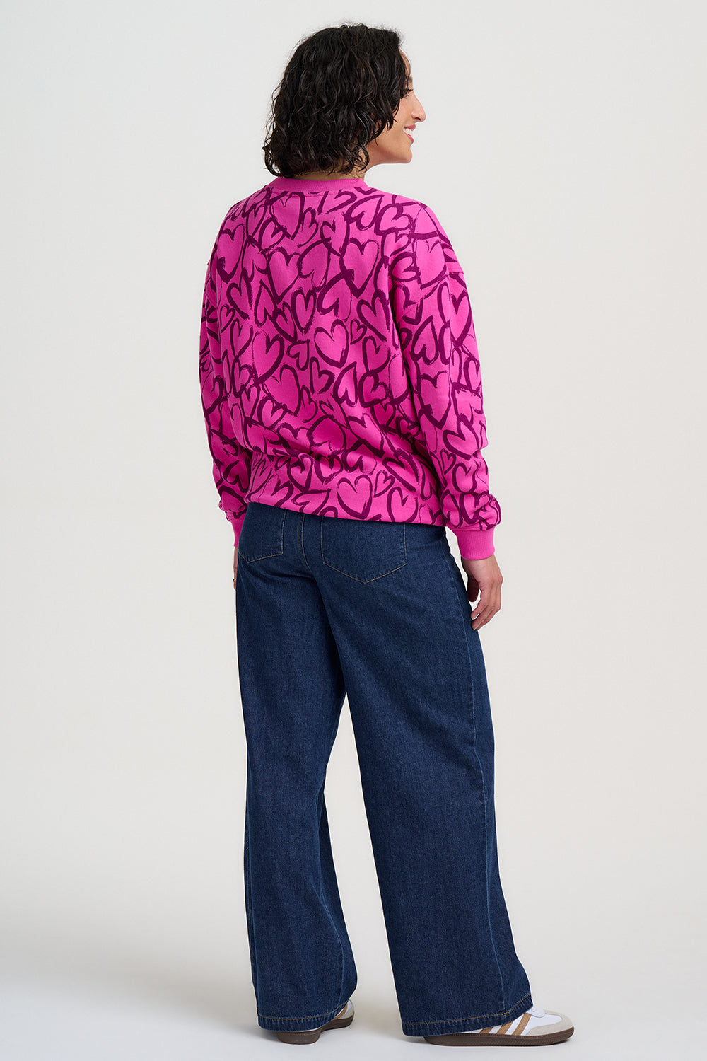 Person wearing a pink patterned shirt and blue jeans on a white background