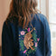 Person wearing a navy blue sweatshirt with a tiger and floral design on the back.