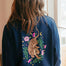 Person wearing a navy blue sweatshirt with a tiger and floral design on the back.