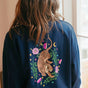 Person wearing a navy blue sweatshirt with a tiger and floral design on the back.