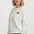 Woman wearing a white sweater with a red horse emblem on a plain background