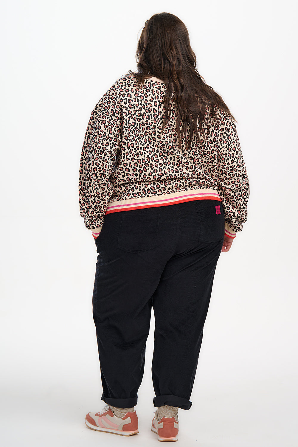 Person wearing a leopard print jacket and black pants on a white background